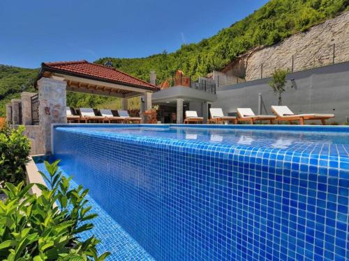 une piscine bleue avec des chaises et une maison dans l'établissement Villa Finca Lazeta, à Studenci
