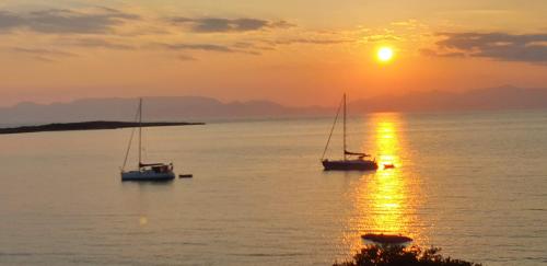 two boats sitting in the water at sunset at Sunset Holiday House in Archangelos
