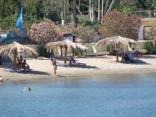 a group of people on a beach with umbrellas at Sunset Holiday House in Archangelos