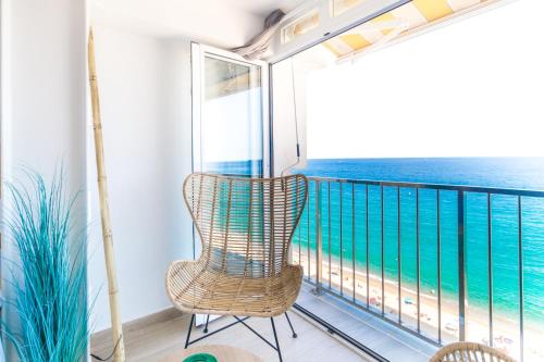 a balcony with a rattan chair and the ocean at Sugar Beach Boutique Studio in Platja  d'Aro