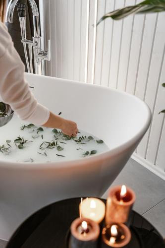 a person standing in a bath tub with candles at Sniegi design cabin with sauna in Madona
