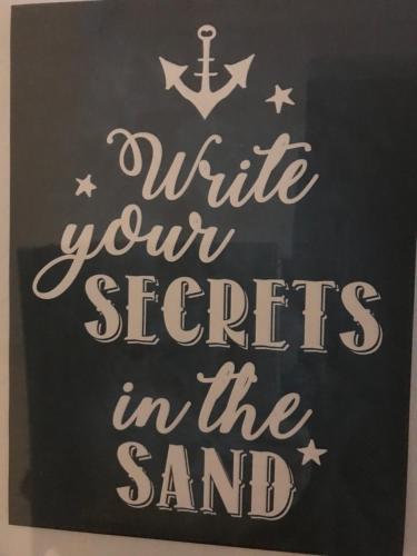 a sign that says write your secrets in the sand at Beachcomber Cottages in Ballyconneely