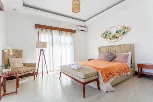 a bedroom with a bed with an orange blanket and a chair at Coca Cabana in Porac