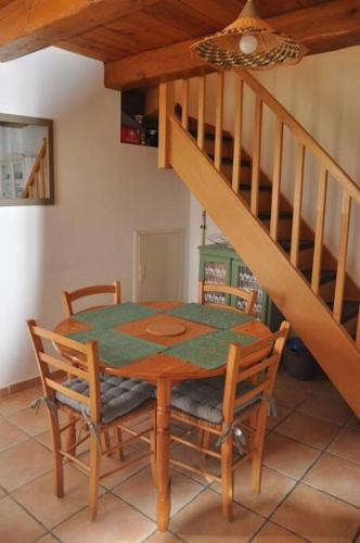 une table et des chaises dans une pièce avec un escalier dans l'établissement Maison en pierre indépendante 47m² + stationnement, à Sillans-la-Cascade