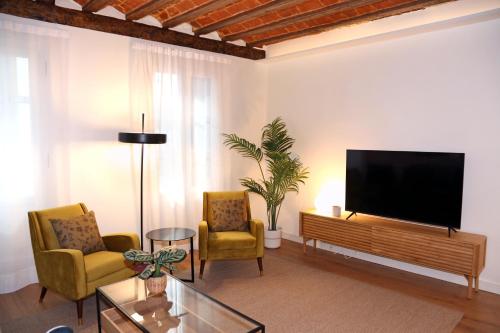 a living room with a flat screen tv and two chairs at Apartamento Premium en Pleno Casco Viejo de Bilbao in Bilbao
