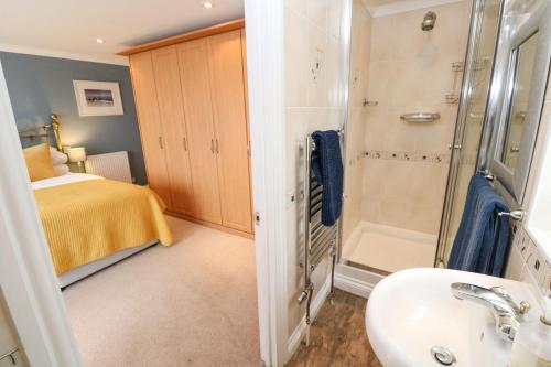 a bathroom with a sink and a shower and a bed at Rosemount in Marazion