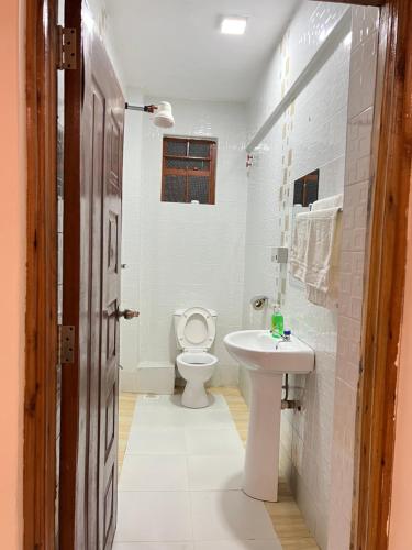 a bathroom with a white toilet and a sink at Regency Stays in Eldoret