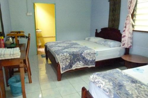 a bedroom with two beds and a table and a table at Cheers Garden Chalet in Kampung Tekek