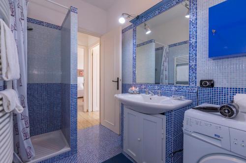 ein blau gefliestes Bad mit einem Waschbecken und einer Dusche in der Unterkunft La Casa Al Sole sea view 400mt from sea - Happy Rentals in Cervo