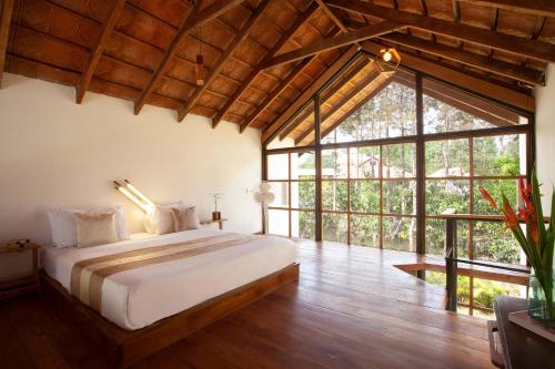 a bedroom with a bed and a large window at StayVista at Cedar - Strelitzia 2BHK with Breakfast and Jacuzzi in Chikmagalur