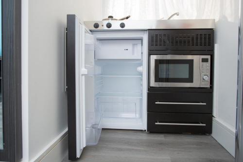 a kitchen with a microwave and an open refrigerator at Legoland Heathrow Windsor Apartment Hotel in Slough