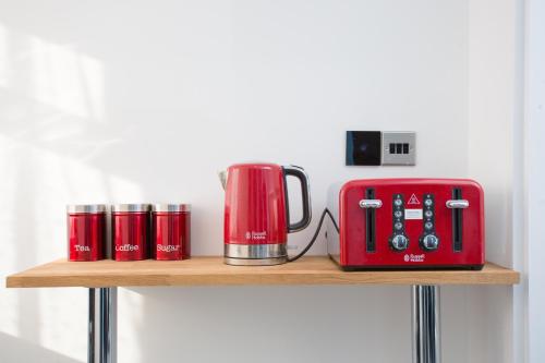 a red appliance sitting on a wooden shelf at Legoland Heathrow Windsor Apartment Hotel in Slough