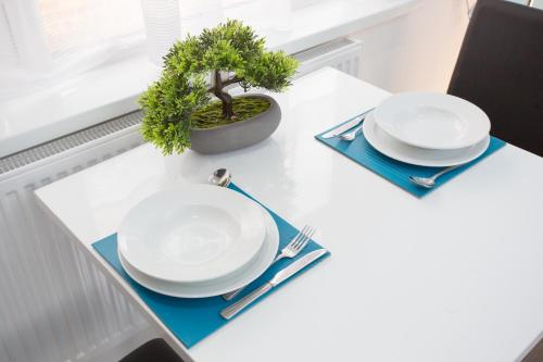 a table with two white plates and a plant on it at Legoland Heathrow Windsor Apartment Hotel in Slough