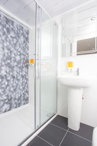 a white bathroom with a shower and a sink at Legoland Heathrow Windsor Apartment Hotel in Slough