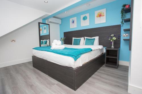 a bedroom with a large bed with blue walls at Legoland Heathrow Windsor Apartment Hotel in Slough