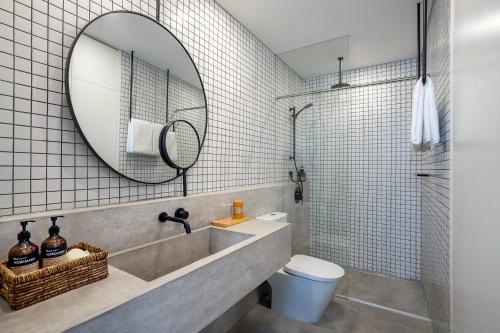 ein Badezimmer mit einem Waschbecken, einem Spiegel und einem WC in der Unterkunft base-PUSAN Serviced Apartment in Shanghai