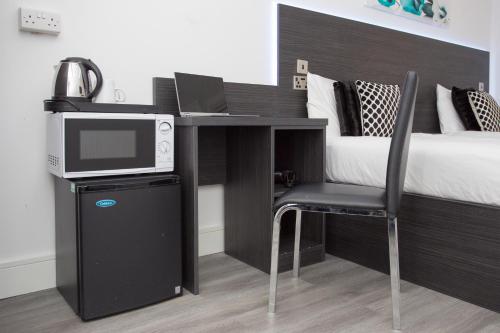 a bedroom with a desk with a microwave and a bed at Legoland Heathrow Windsor Apartment Hotel in Slough