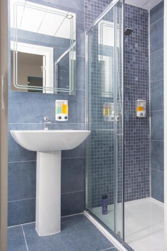 a bathroom with a sink and a glass shower at Legoland Heathrow Windsor Apartment Hotel in Slough