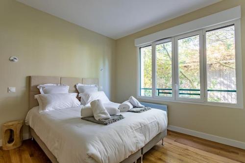 una camera da letto con letto, lenzuola bianche e finestre di O'DUNE Pyla Plage -appartement jacuzzi vue mer - a Pyla-sur-Mer