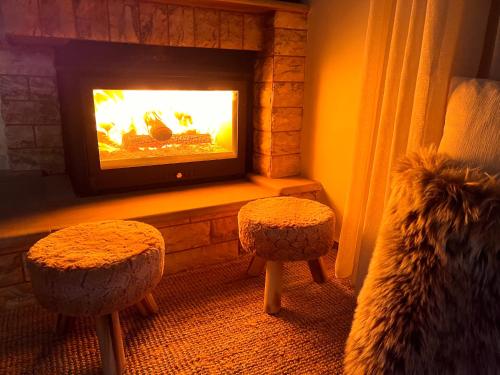 a living room with a fireplace with two stools and a couch at Ski Suites - A Luxury Maisonette Kalavryta in Kalavrita