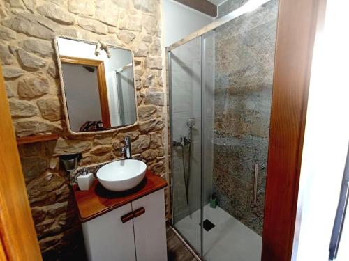 La salle de bains en pierre est pourvue d'un lavabo et d'une douche. dans l'établissement Cabaña de Piedra en Picos de Europa, à Arenas de Cabrales