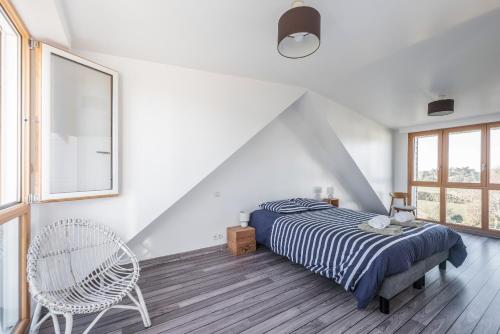 een witte slaapkamer met een bed en een stoel bij Ker Kast - Grande maison proche plage in Saint-Cast-le-Guildo