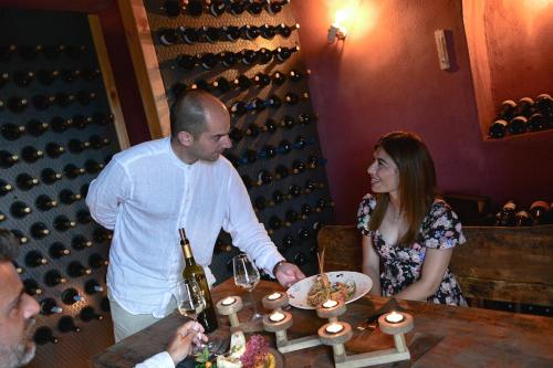 a man and woman standing at a table with a plate of food at White Pearl Cavalieri in Imerovigli