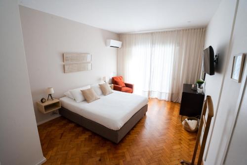 a bedroom with a white bed and an orange chair at Alegria Cozy com Terraço - Centro do Porto in Porto