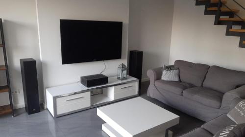 a living room with a couch and a flat screen tv at Dom Dąbrówka Poznań in Palędzie