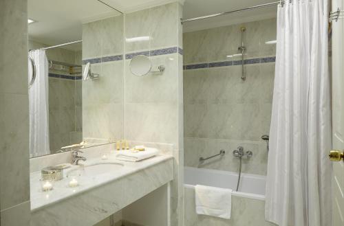a white bathroom with a sink and a shower at Mediterranean Palace in Thessaloniki