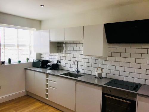 a kitchen with white cabinets and a counter top at West Cliff Apartment in Bournemouth