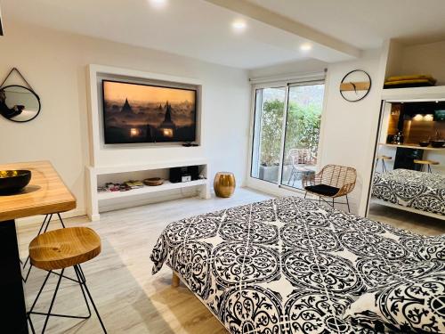 een slaapkamer met een bed en een televisie aan de muur bij Feel@Home Nemausus « Le 42 » in Nîmes