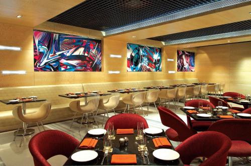a restaurant with tables and chairs and paintings on the walls at Vivanta Hyderabad, Begumpet in Hyderabad