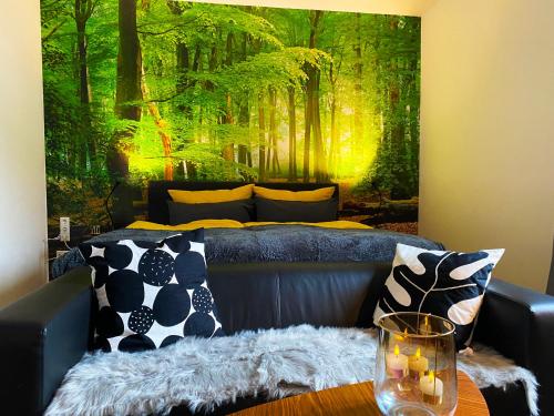 Wood-Appartement في بيليفيلد: غرفة معيشة مع أريكة وجدارية غابة