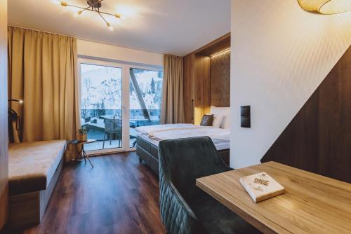 a hotel room with a bed and a table at GLEMM by AvenidA Superior Hotel & Residences in Saalbach Hinterglemm