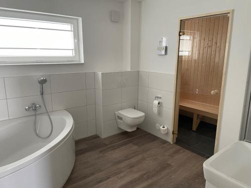 a bathroom with a tub and a toilet and a sink at 50 3 N Nordkoje in Wangerland