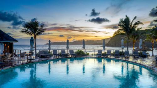 a swimming pool with chairs and the ocean in the background at Hotel Manapany in Gustavia