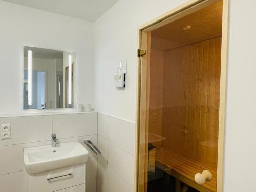a white bathroom with a sink and a shower at 49 5 M Ankerplatz in Wangerland