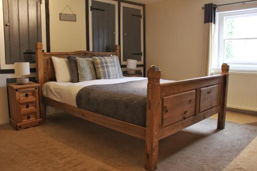Un dormitorio con una gran cama de madera y una ventana en The Ibex Inn en Newbury