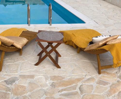 stół i 2 krzesła przy basenie w obiekcie MiaBella Resort w mieście Drage