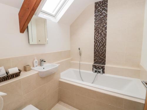 a bathroom with a bath tub and a sink at Grange Cottages in Alnwick
