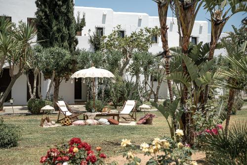 a garden with two chairs and an umbrella at Geraniotis Hotel and Resort in Plataniás