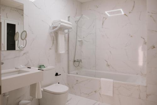 a white bathroom with a shower and a toilet and a sink at Hotel Melilla Centro in Melilla