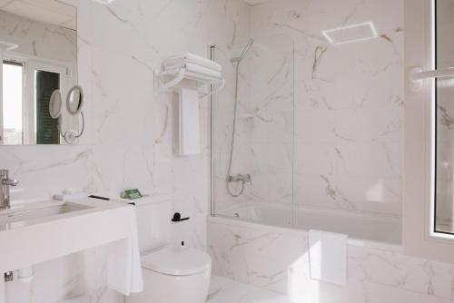 a white bathroom with a shower and a toilet and a sink at Hotel Melilla Centro in Melilla