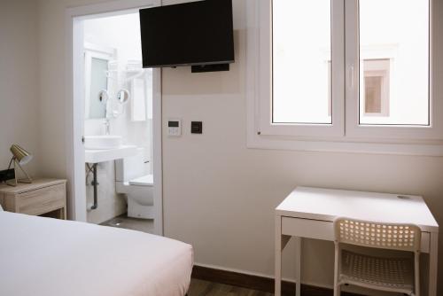 1 dormitorio con cama, escritorio y lavamanos en Melilla Centro Hotel *** en Melilla