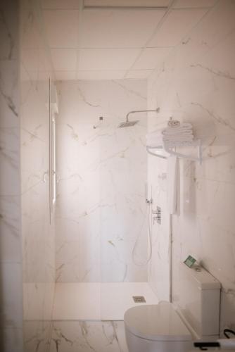 a white bathroom with a shower and a toilet at Hotel Melilla Centro in Melilla