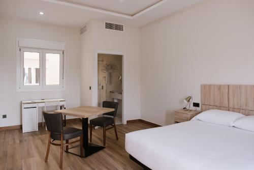 1 dormitorio con 1 cama, mesa y sillas en Melilla Centro Hotel *** en Melilla