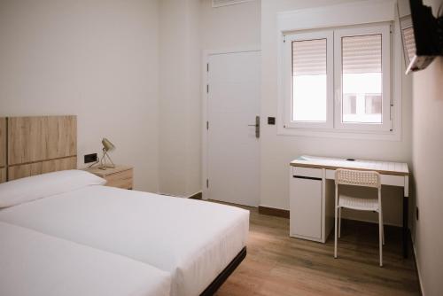 a bedroom with a bed and a desk and a window at Hotel Melilla Centro in Melilla