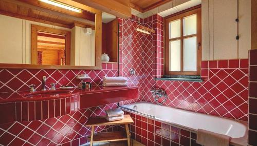 W wyłożonej czerwonymi kafelkami łazience znajduje się wanna i umywalka. w obiekcie Hotel Breithorn w mieście Champoluc