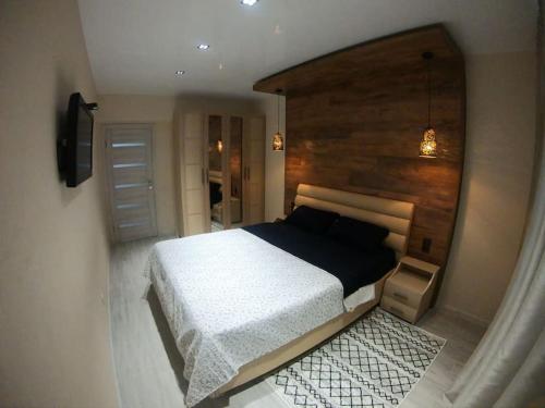 ein Schlafzimmer mit einem großen Bett und einer Holzwand in der Unterkunft Новая, уютная квартира по ул. Grenoble 120/10 in Chişinău